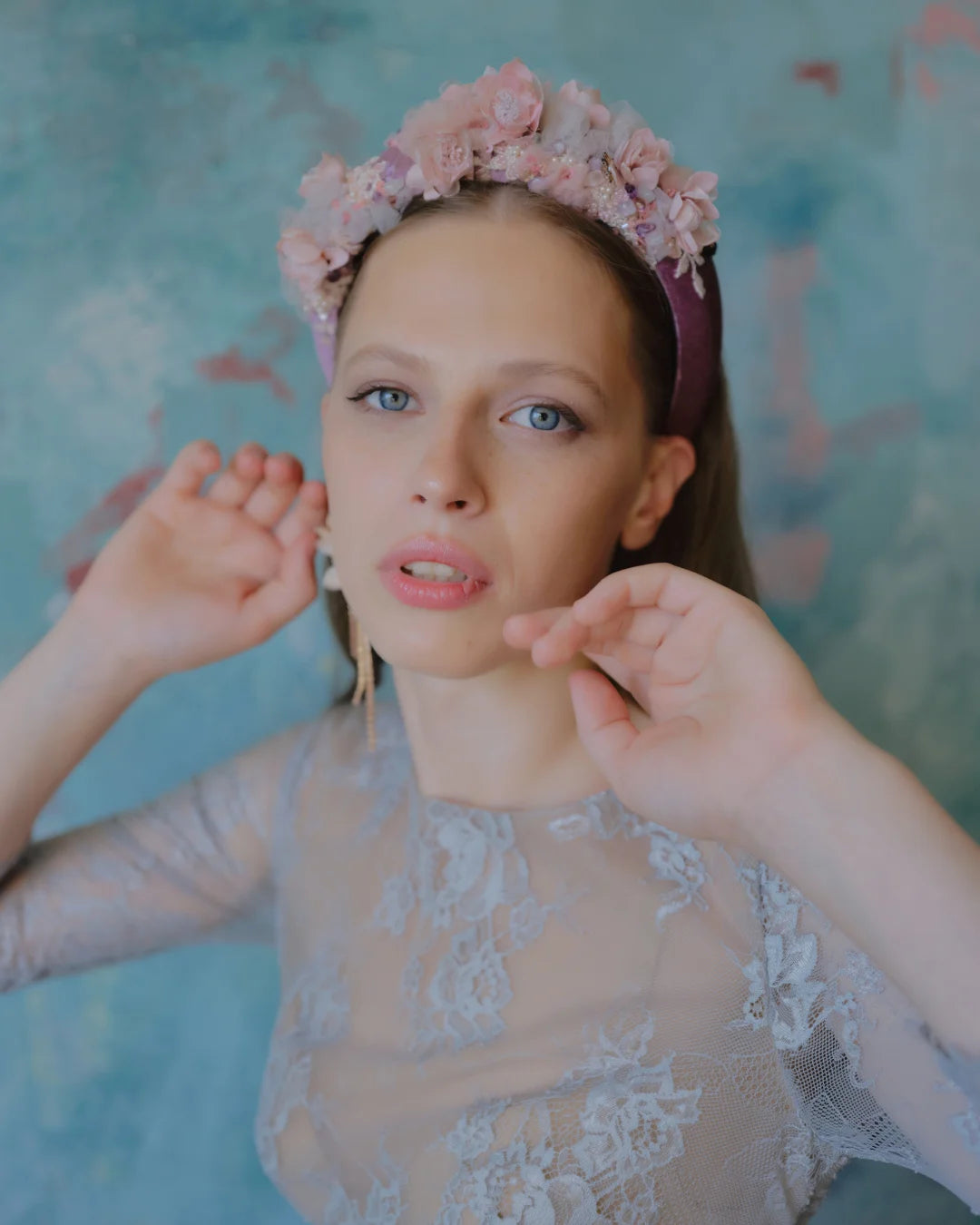 Editorial-style close-up of model showcasing pink flower crown headband and statement floral earrings.