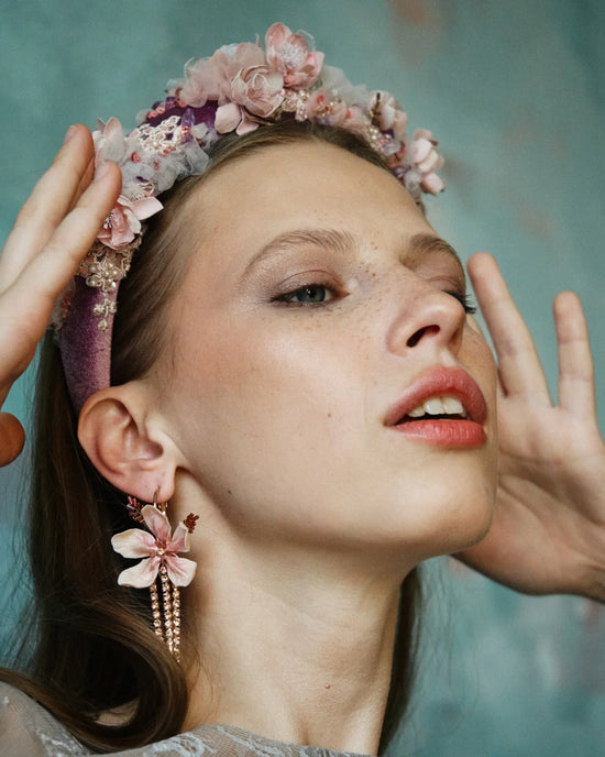 Artistic portrait showing intricate floral headpiece with velvet base and embroidered petals in mauve tones.