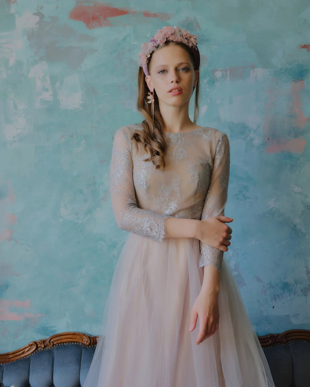 Bride in full-length view wearing a dramatic mauve padded bridal crown and romantic long-sleeve lace gown.