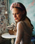 Close-up of handmade bridal headband with pink and mauve flowers, worn with loose waves and lace gown.