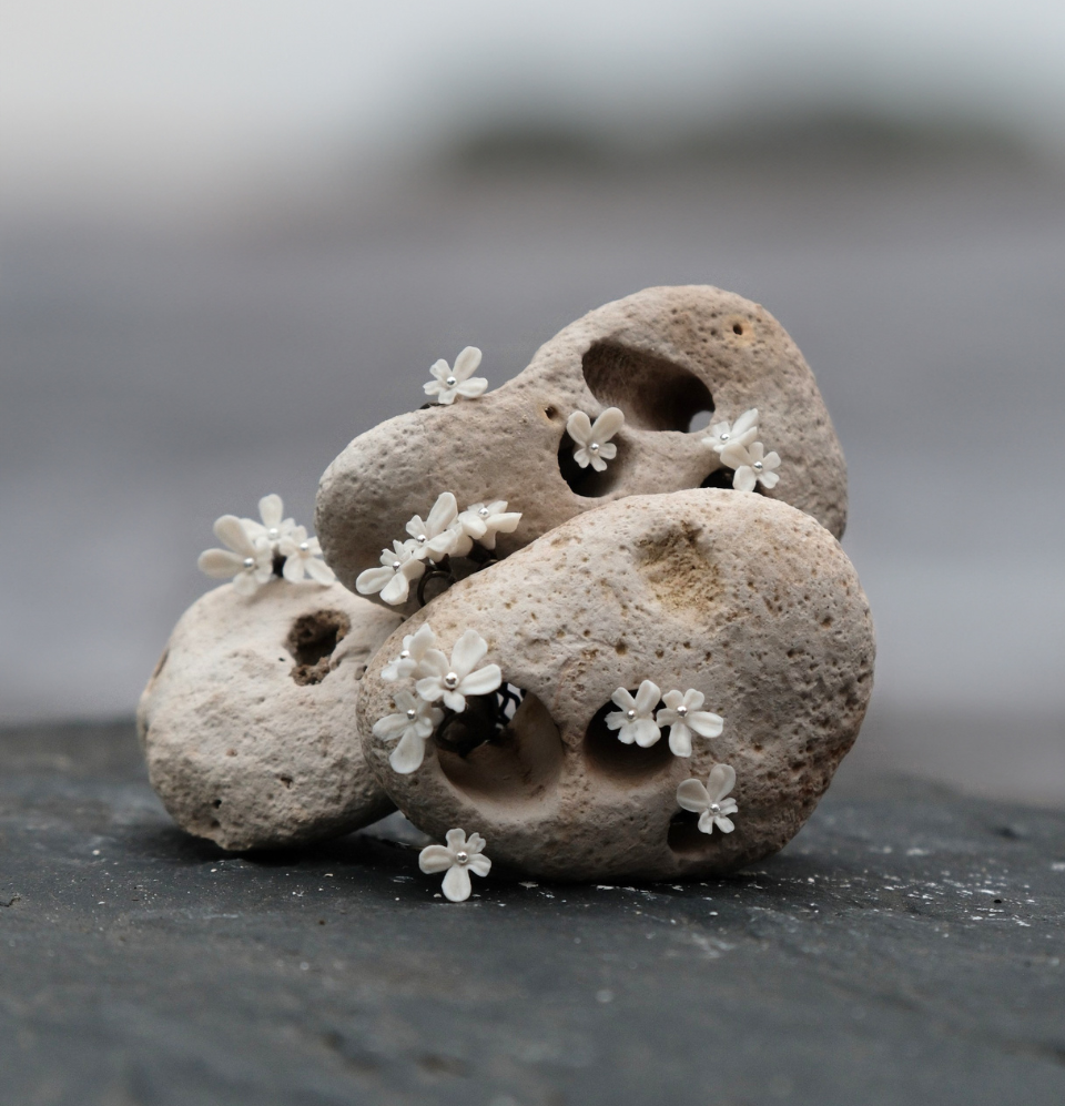 Handcrafted tiny white lavender flower hair pins with silver centers, arranged on natural textured stones, Decoflowers bridal accessories UK.