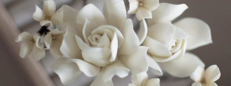 Close-up of handmade white floral bridal hair accessory by DecoFlowers, sculpted from polymer clay in a lifelike rose shape.