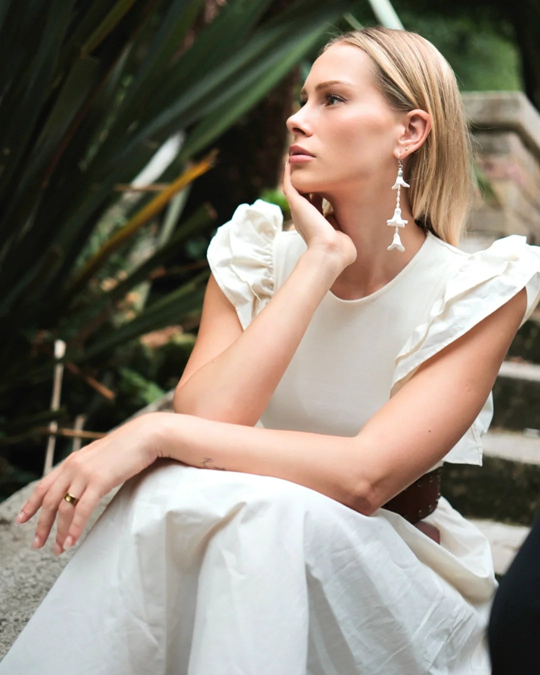 Side profile of a bride with blonde hair wearing a single long white hyacinth floral wedding earring made of handmade foam flowers and sterling silver, elongating the neck. Minimalist bridal look by Deco Flowers.