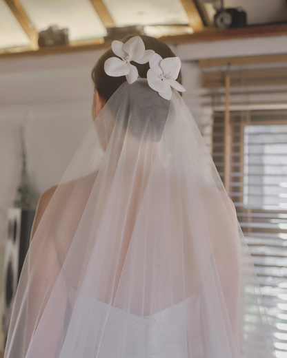 Pair of white orchid bridal hair flowers adorning a veil